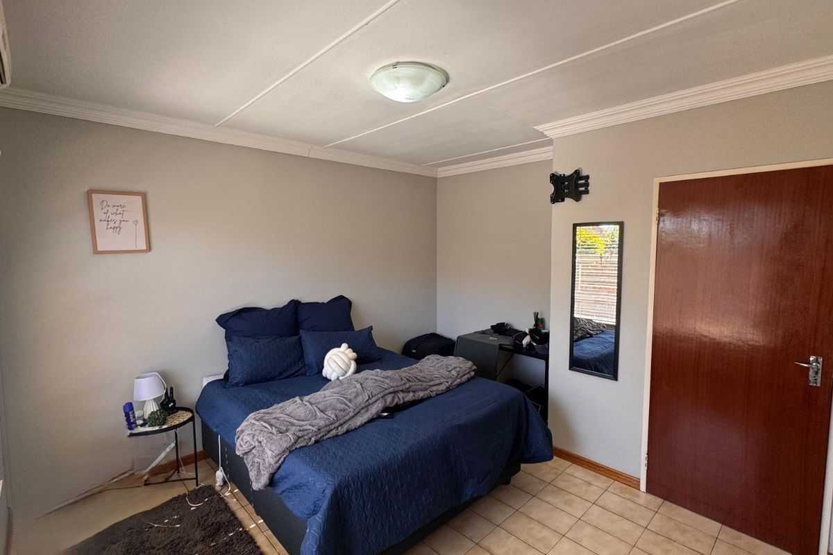 A functional bedroom featuring tiled flooring, ceiling cornice detailing, and an integrated air conditioning unit.