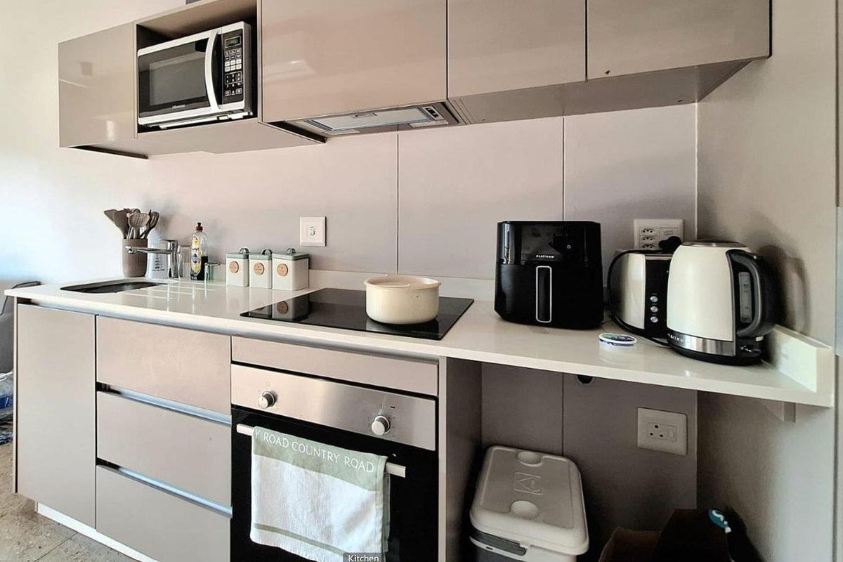 Modern kitchen featuring sleek cabinetry, stone countertops, integrated microwave, electric hob, and built-in oven, providing a clean and functional cooking space.