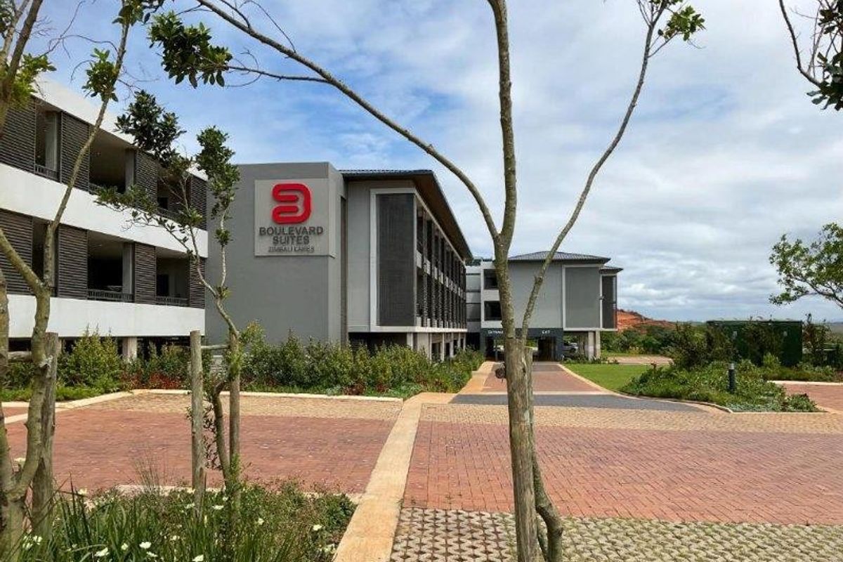 Exterior view of the Boulevard Suites apartment complex, featuring modern architectural design, paved driveway, and well-maintained landscaped grounds.