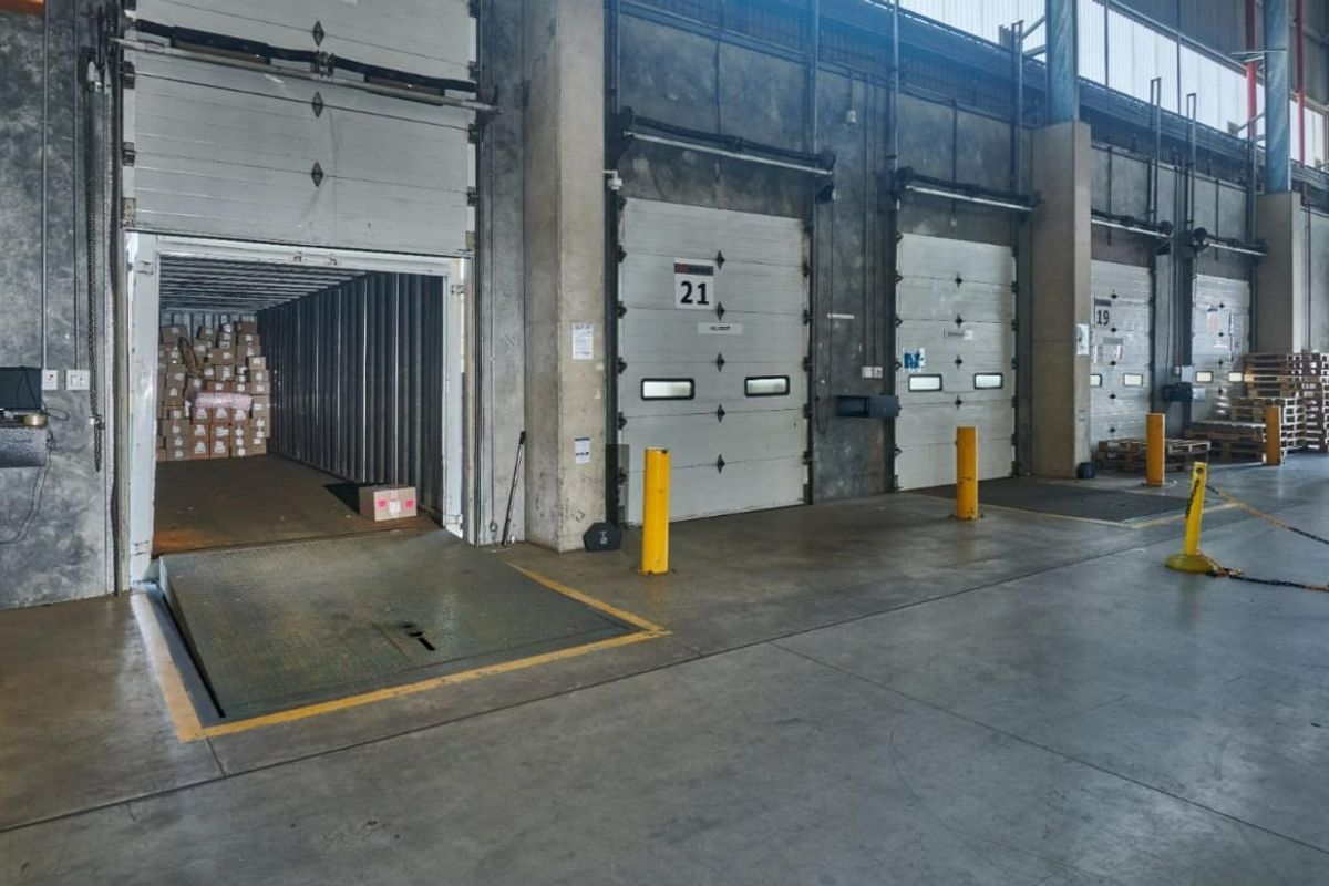 Commercial warehouse loading bay area featuring multiple industrial roller shutter doors, dock levelers, and durable concrete flooring for efficient logistics operations.