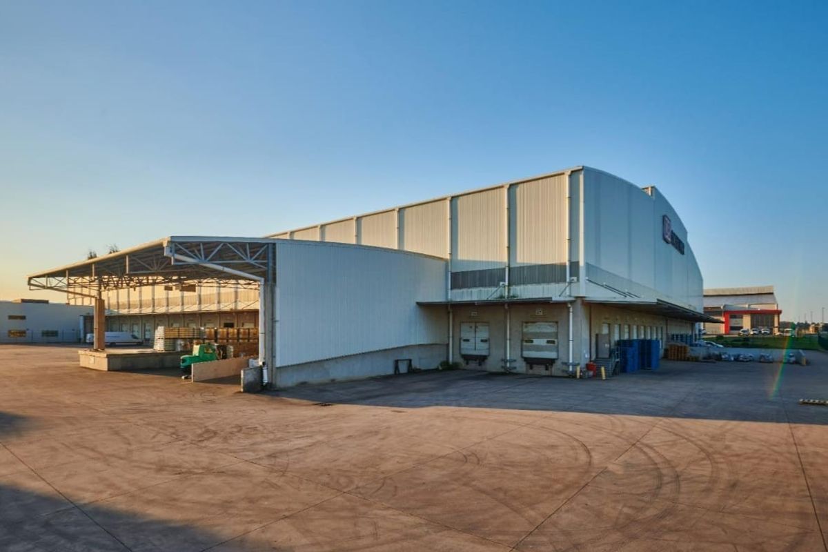 Commercial warehouse facility featuring multiple loading docks, a large concrete yard, and a covered loading canopy for efficient logistics operations.