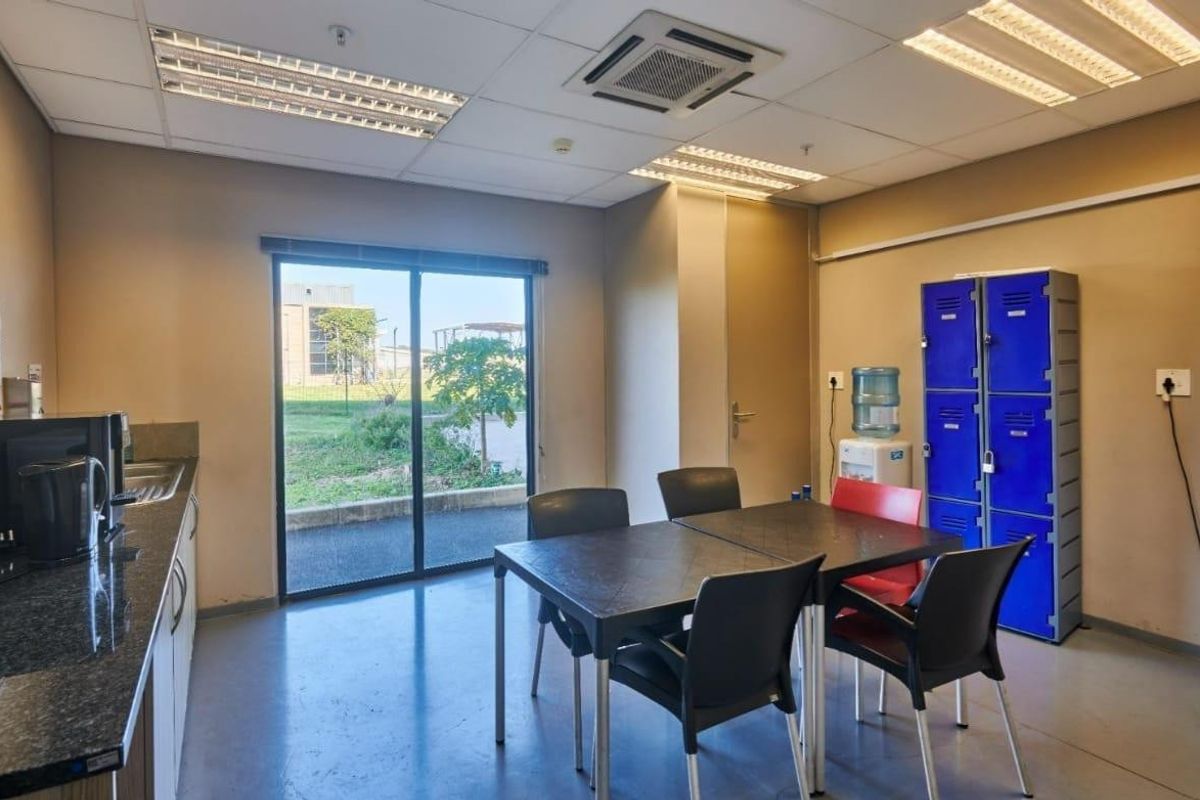 A functional commercial kitchen and break area featuring granite countertops, built-in cabinetry, and direct access to an outdoor area via a sliding glass door.