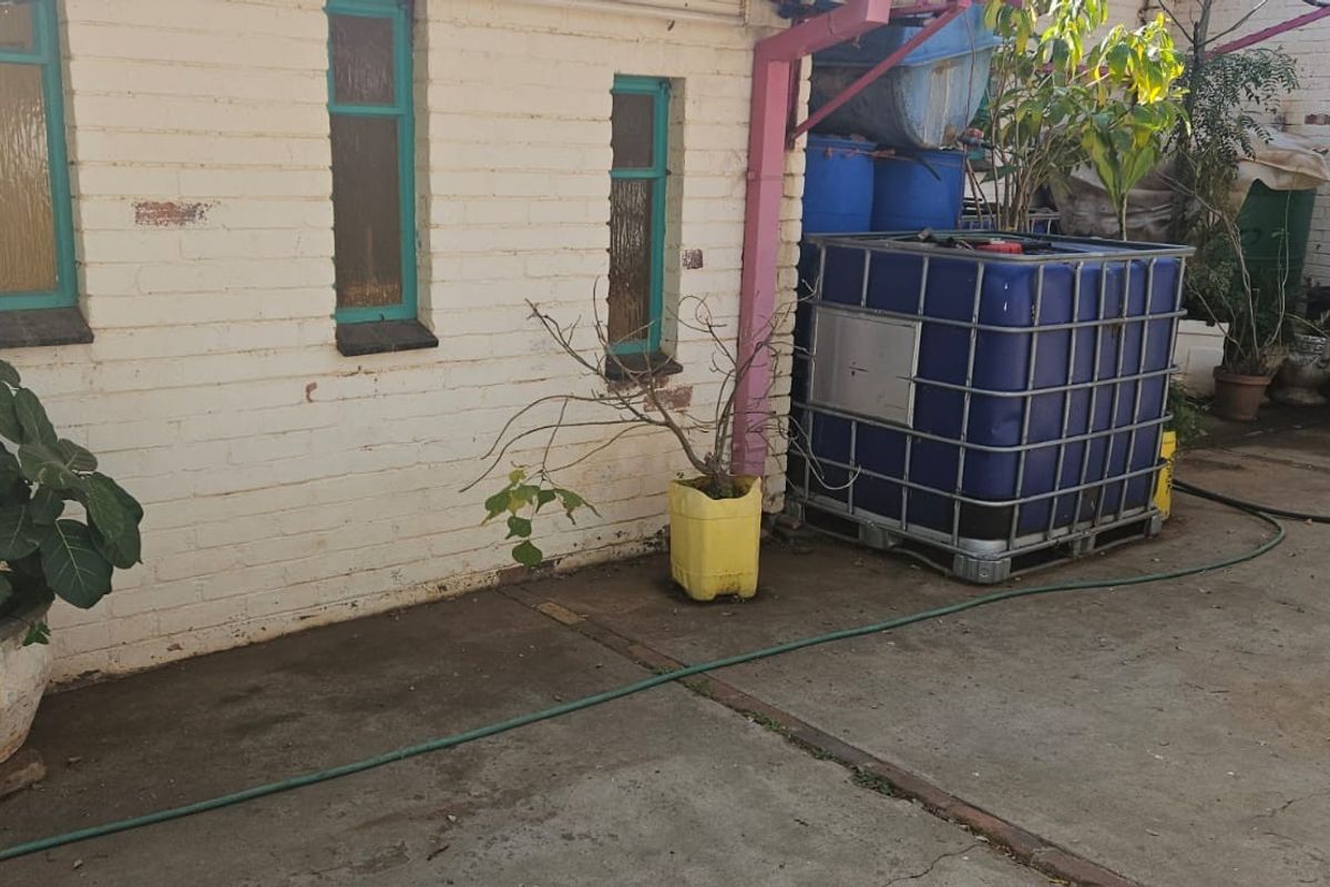 Rear exterior area featuring painted brick walls, concrete paving, and a large water storage tank.