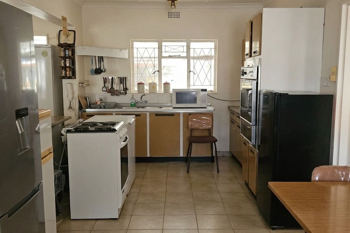 A functional kitchen featuring dated cabinetry, tiled flooring, and built-in oven, offering potential for modernization and aesthetic updates.