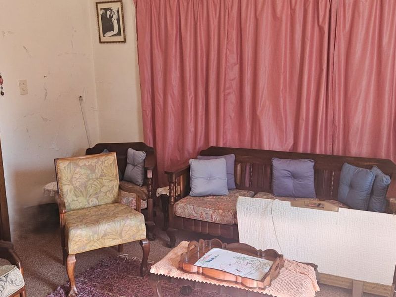 A living room space featuring carpeted flooring and a solid wood door, currently showing signs of wear on the wall surfaces.