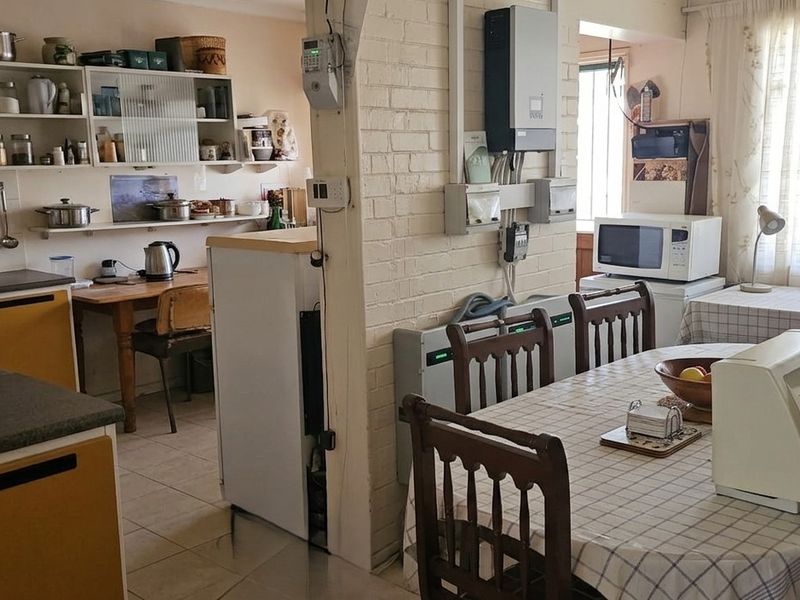 Open-plan kitchen and dining area featuring exposed brickwork, tiled flooring, and functional cabinetry, offering potential for a modern renovation.