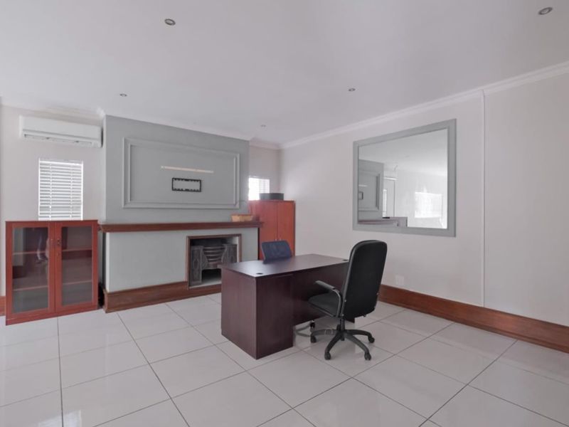 A professional office space featuring tiled flooring, a built-in fireplace, air conditioning, and recessed lighting, providing a clean and functional work environment.