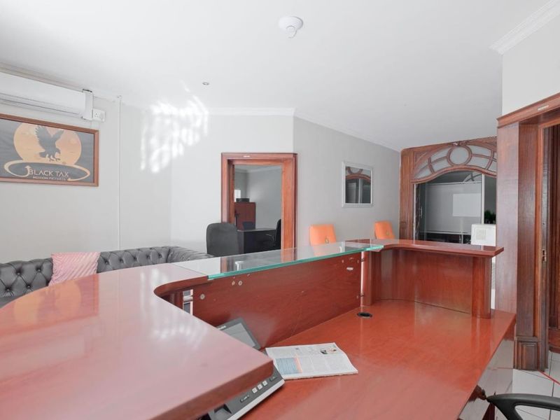 A professional commercial reception area featuring a large built-in wooden desk, classic timber door frames, and integrated air conditioning.