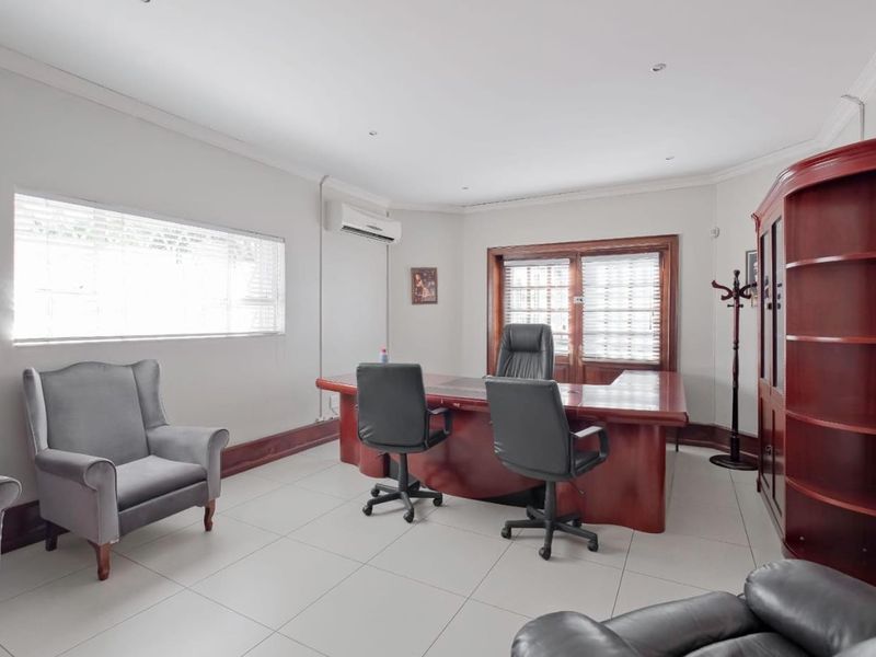 A professional office space featuring tiled flooring, recessed lighting, and a wall-mounted air conditioning unit.