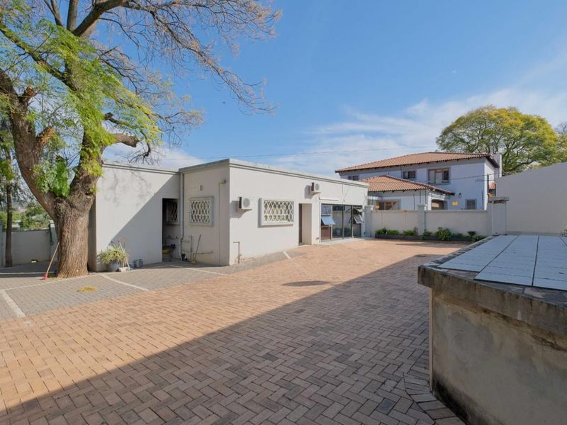 A spacious paved rear courtyard area featuring a built-in tiled counter, security-fitted windows, and perimeter boundary walls.