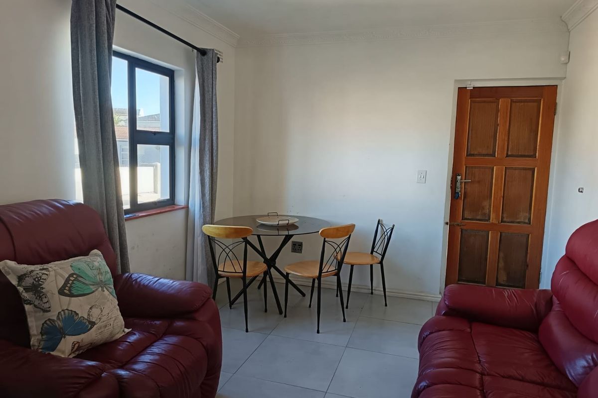 A living area featuring tiled flooring, a timber panel door, and an aluminium window frame with neutral wall finishes.