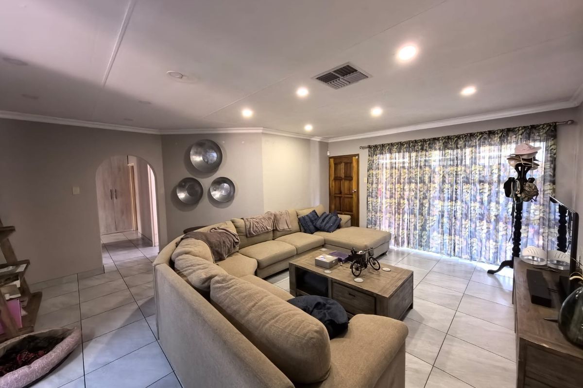 Spacious living room featuring neutral tiled flooring, recessed downlighting, ducted air conditioning, and an arched entryway leading to adjacent areas.