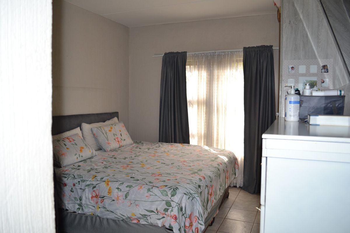 A bedroom featuring tiled flooring and window curtain tracks, providing a functional space with natural light.