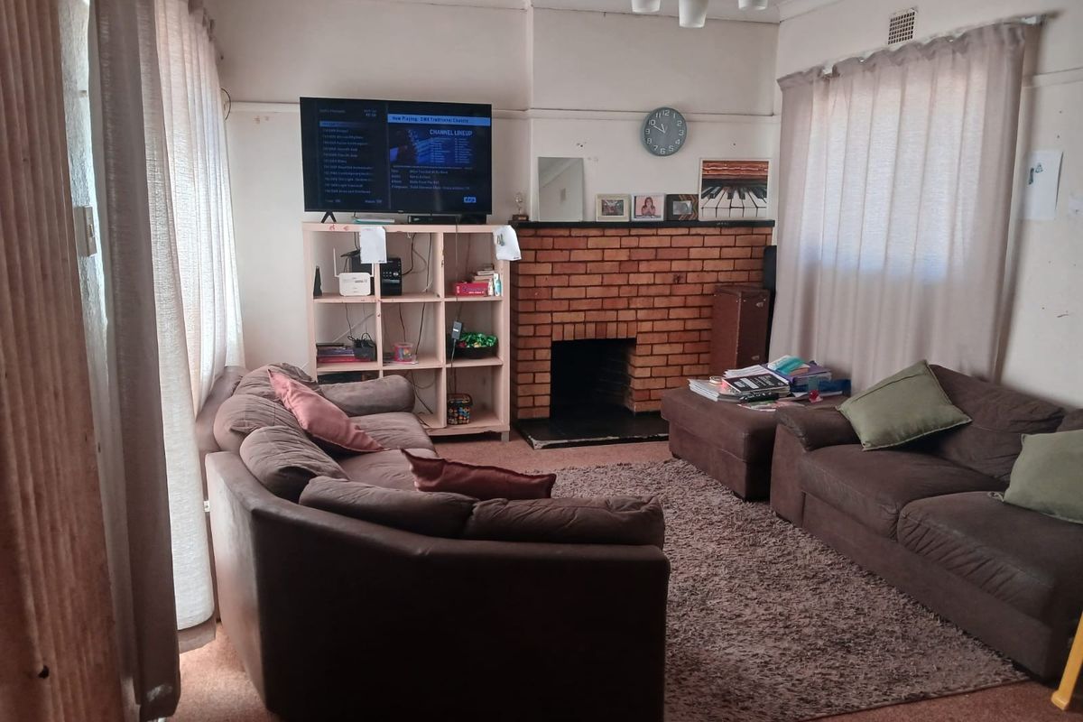 A living room featuring a traditional brick fireplace and hearth, with neutral wall finishes and carpeted flooring.
