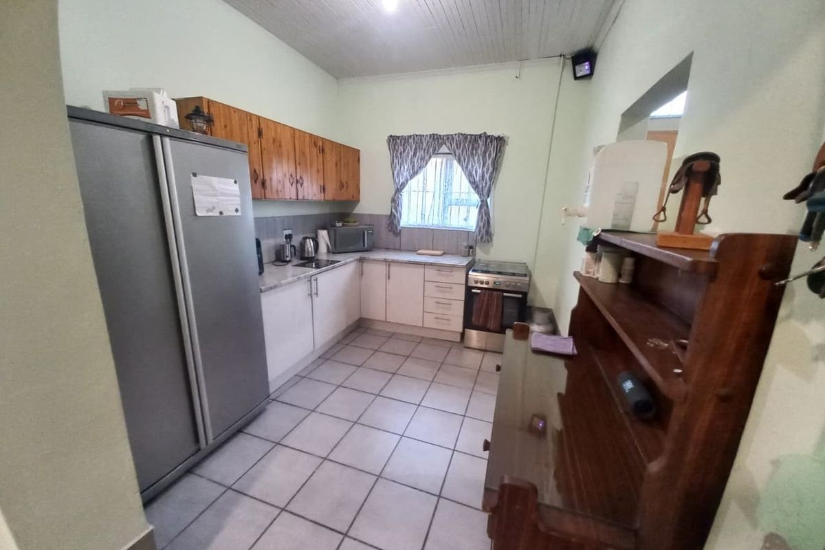 A functional kitchen featuring tiled flooring, built-in cabinetry with laminate countertops, and a freestanding stove, offering a practical layout for daily meal preparation.