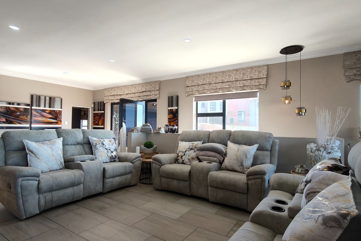Spacious living room featuring neutral wall tones, large format floor tiles, recessed lighting, and sliding glass doors providing access to the exterior.