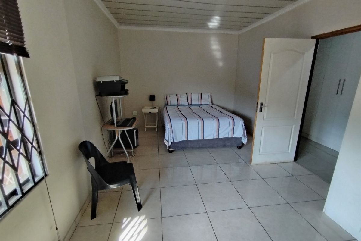 A functional bedroom featuring tiled flooring, a panelled ceiling, and a built-in cupboard, offering a clean and simple living space.