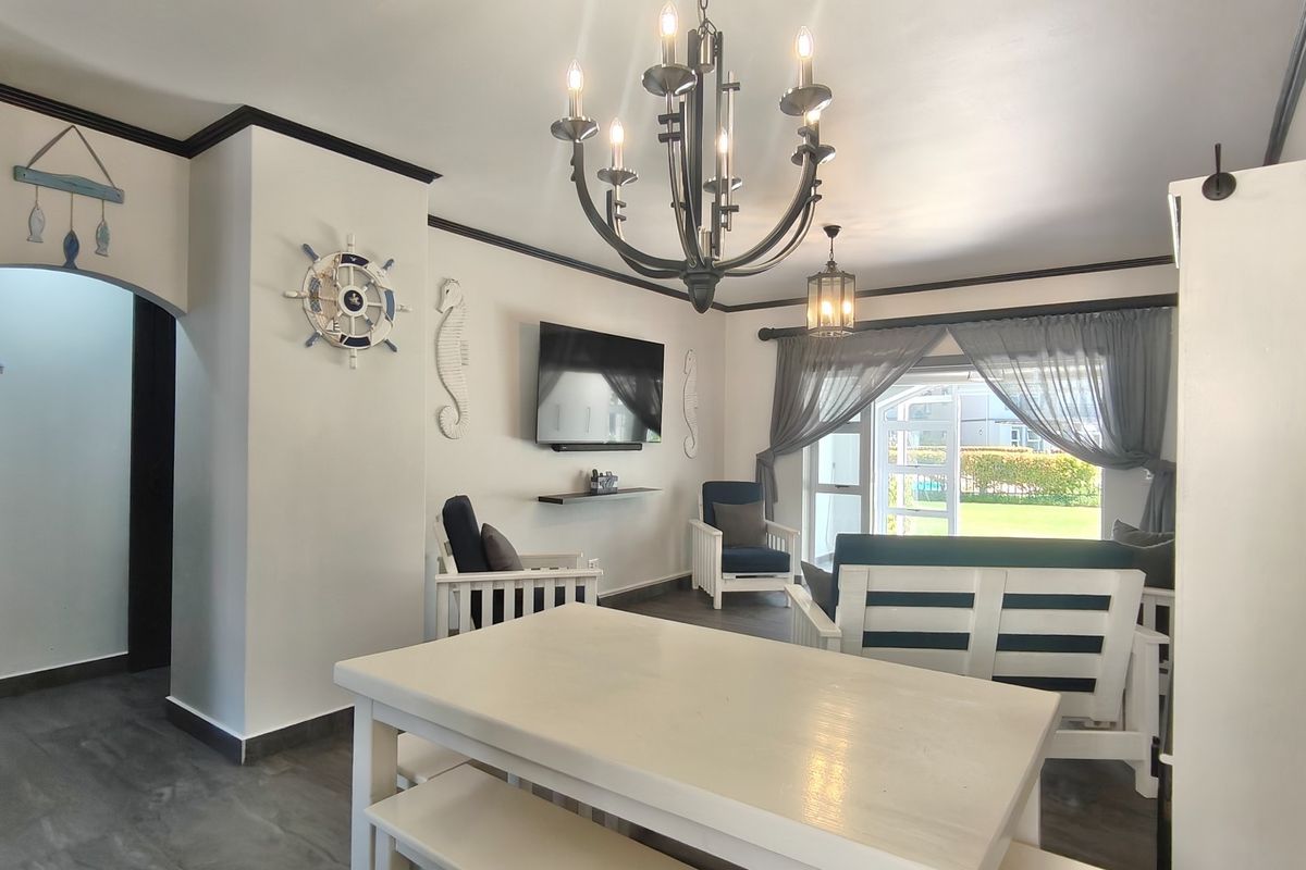 A bright living room featuring crown molding, a decorative chandelier, and a sliding glass door providing access to the outdoor area.