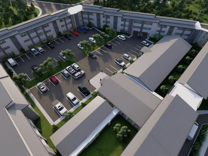 Aerial view of a retirement village complex featuring multi-story residential buildings, extensive paved parking areas, and landscaped grounds.