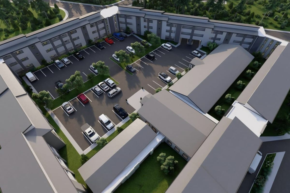 Aerial view of a retirement village complex featuring multi-story residential buildings, extensive paved parking areas, and landscaped grounds.