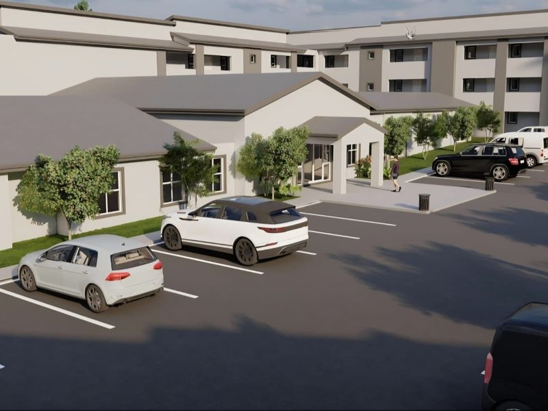 A digital rendering of a retirement village exterior featuring a paved parking area and a modern building facade with a covered entrance.