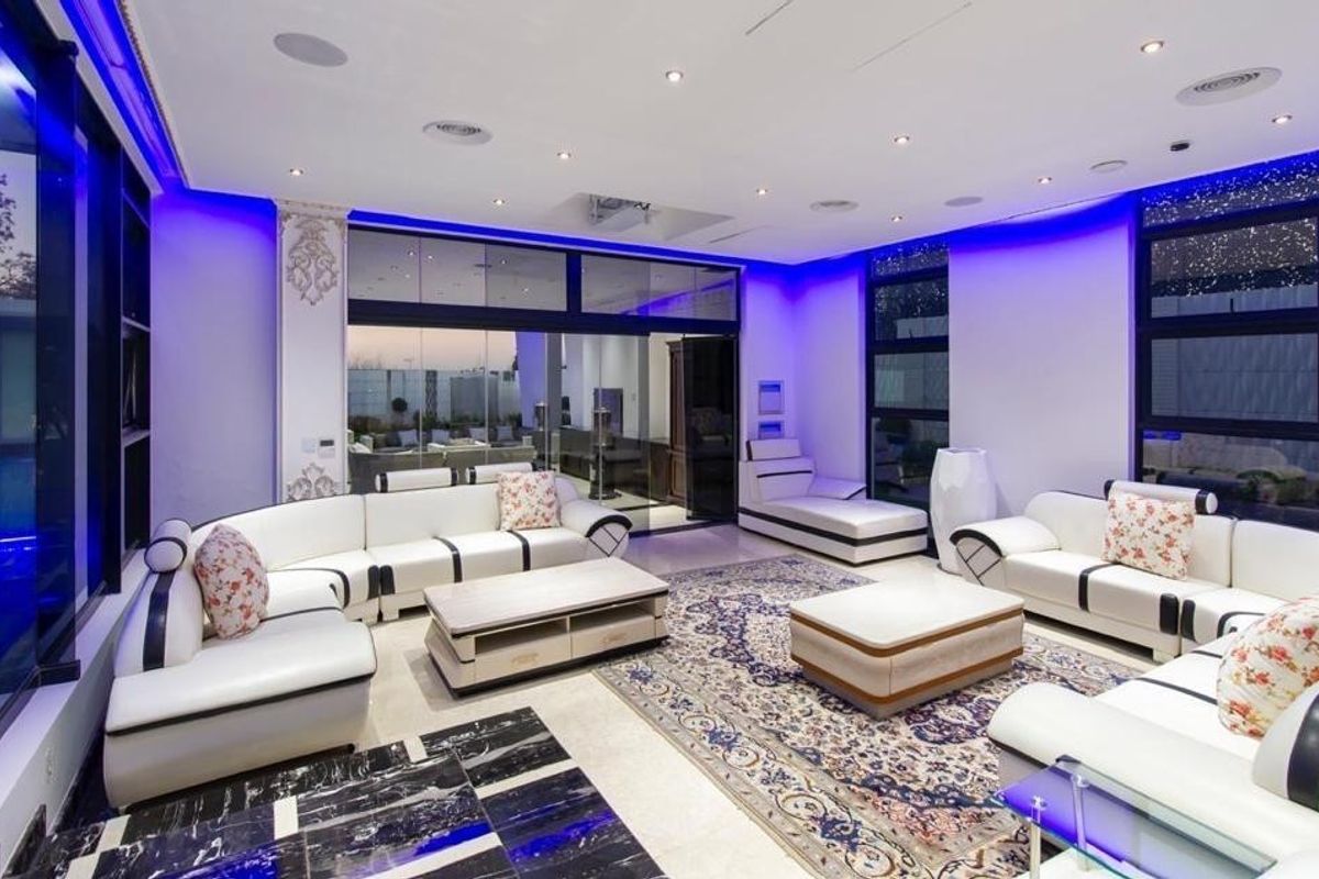 Spacious modern living room featuring high-end finishes, recessed ceiling lighting, integrated speakers, and large sliding glass doors opening to the exterior.