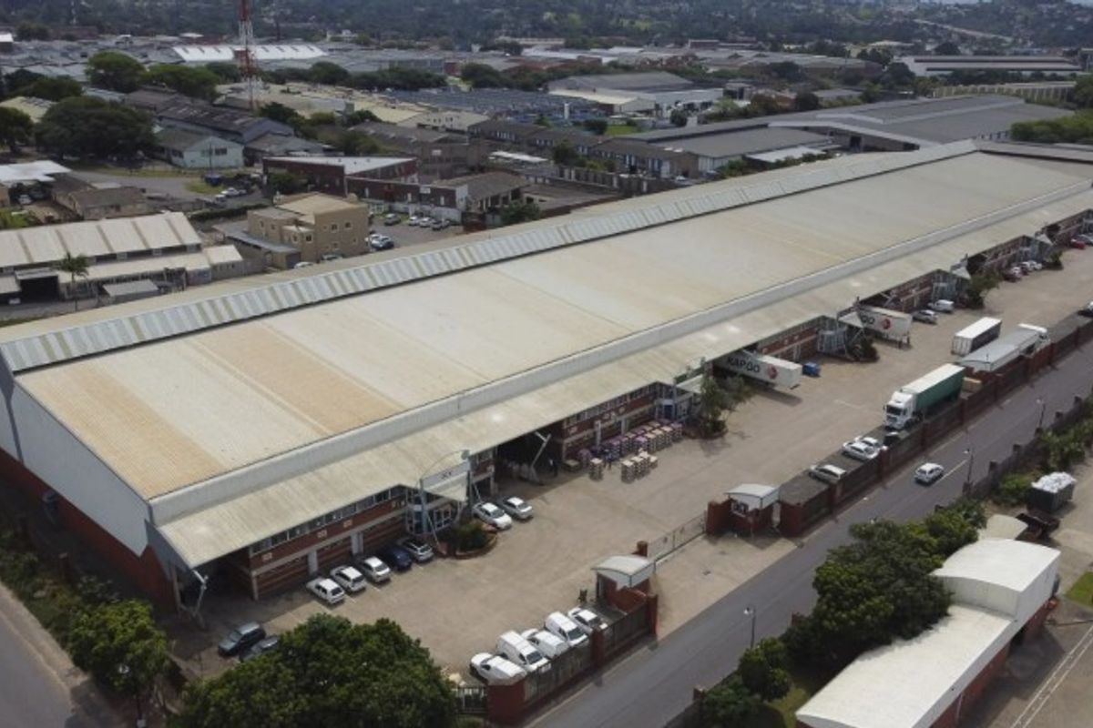 Aerial view of a large industrial warehouse facility featuring extensive roof coverage, multiple loading bays, and a paved yard area for logistics operations.