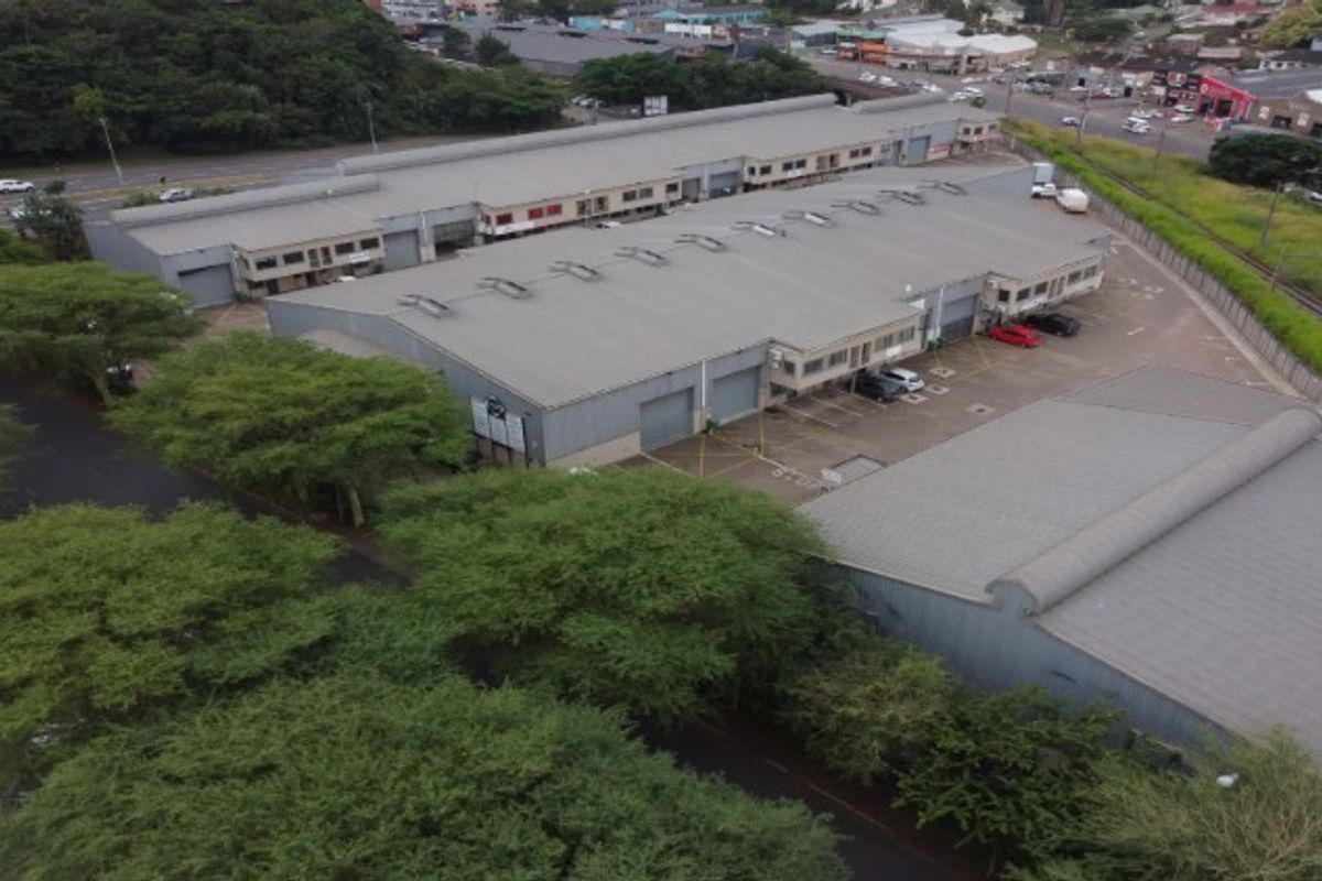 Aerial view of an industrial complex featuring multiple warehouse units, metal roofing, roller shutter doors, and dedicated parking facilities.