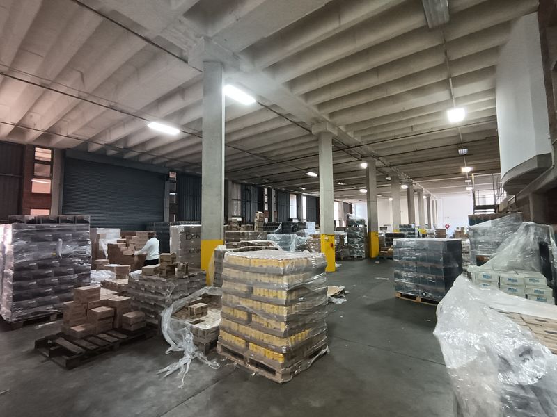 Spacious industrial warehouse area featuring high concrete ceilings, structural columns, and durable concrete flooring, suitable for storage or logistics operations.