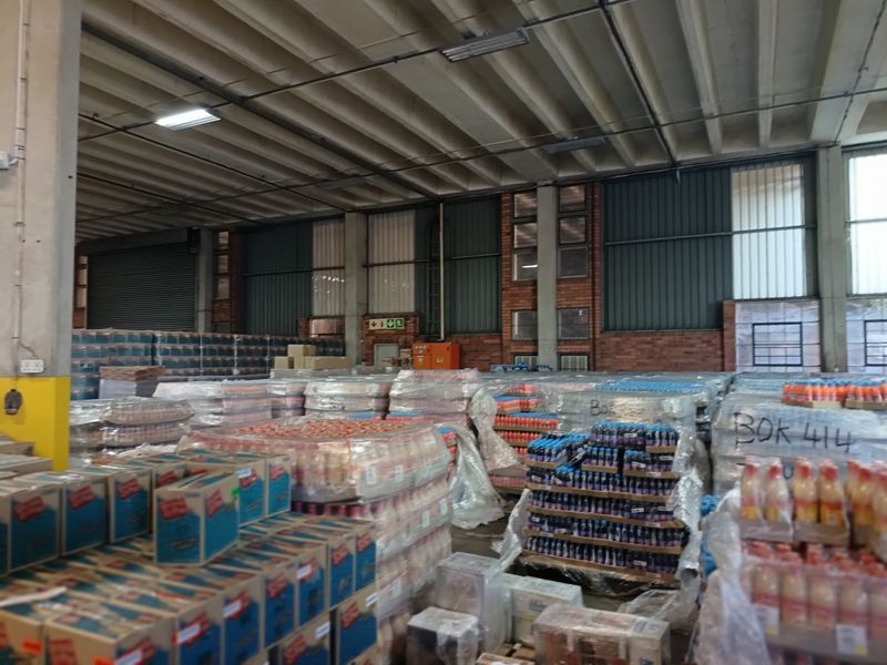 A large industrial warehouse space featuring high exposed concrete ceilings, brick wall detailing, and functional roller shutter access.