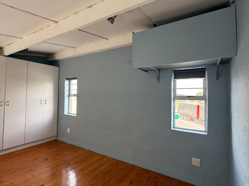 An empty bedroom featuring polished timber flooring, built-in cupboards, and exposed ceiling beams, offering a blank canvas for potential interior updates.