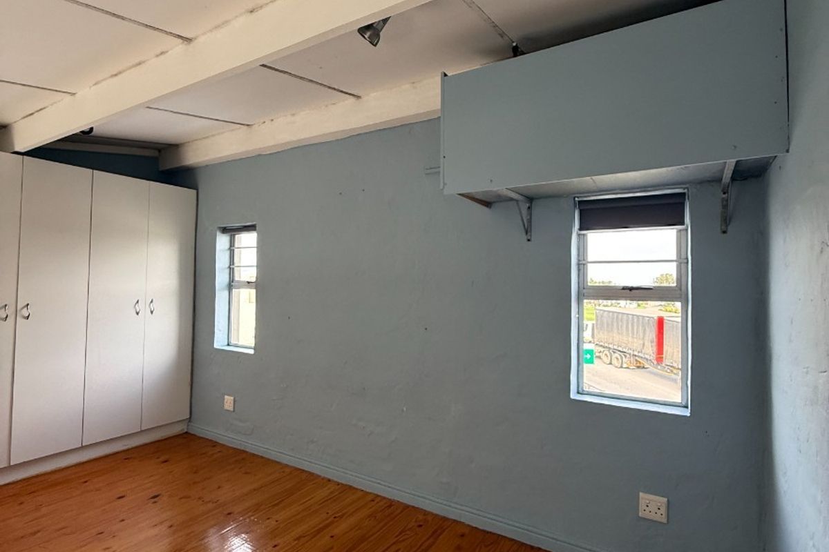 An empty bedroom featuring polished timber flooring, built-in cupboards, and exposed ceiling beams, offering a blank canvas for potential interior updates.