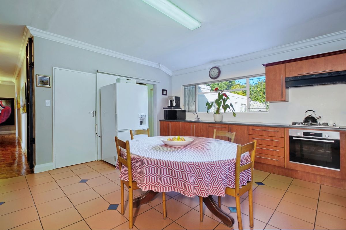 A functional kitchen featuring wooden cabinetry, built-in oven with gas hob, tiled flooring, and a bright, open layout with direct access to adjacent areas.