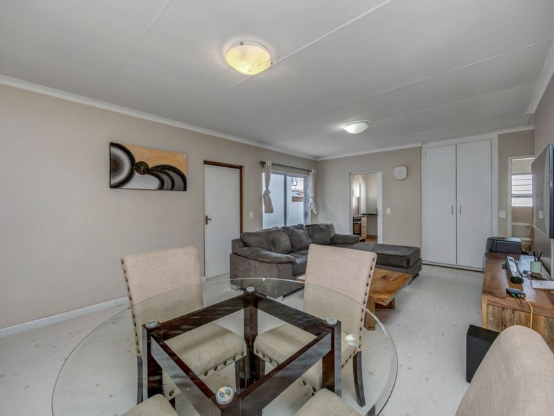 Open plan living and dining area featuring neutral wall tones, built-in storage cupboards, and access to adjacent rooms.