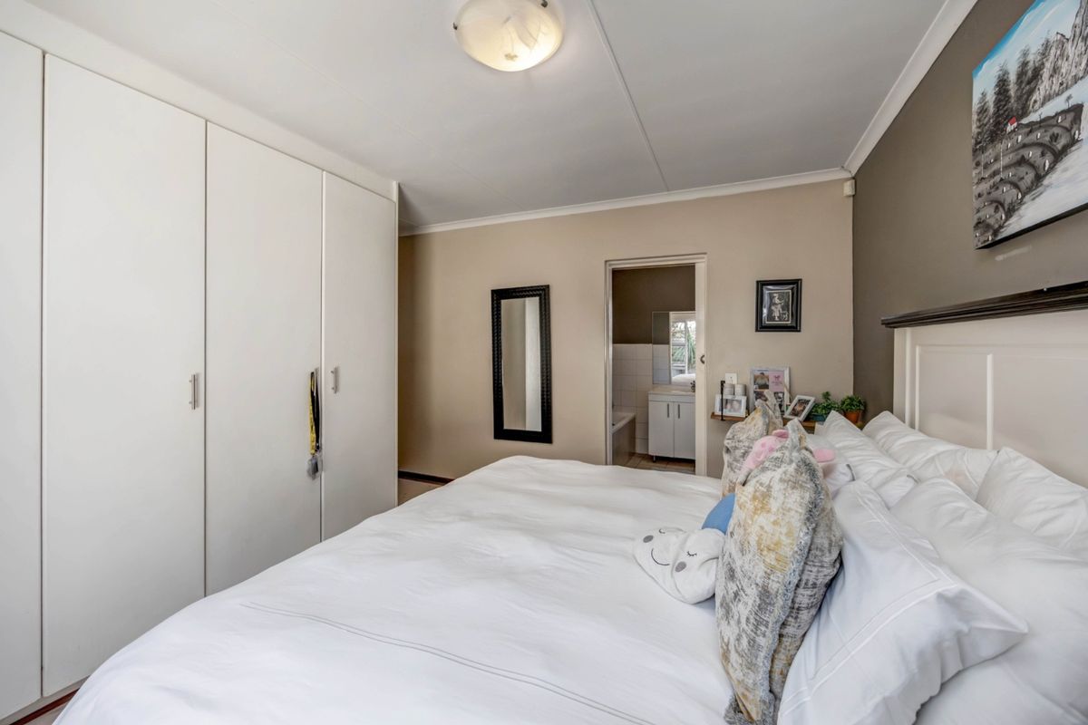 A well-maintained bedroom featuring built-in cupboards and direct access to an en-suite bathroom, offering a functional and comfortable living space.
