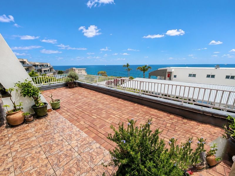 Spacious open-air balcony featuring brick and tile flooring with a metal balustrade, offering expansive ocean views.