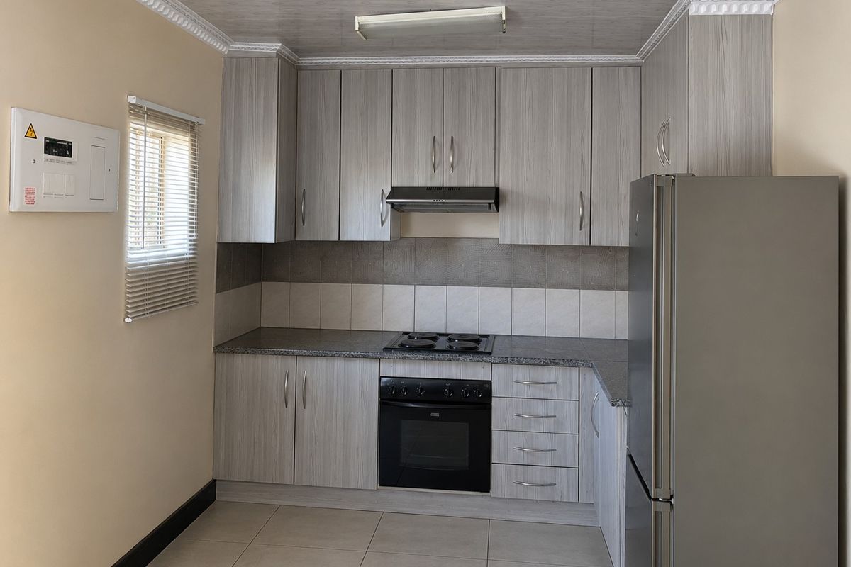 A well-maintained kitchen featuring light wood-grain cabinetry, granite-look countertops, a built-in oven with hob, and a tiled backsplash.