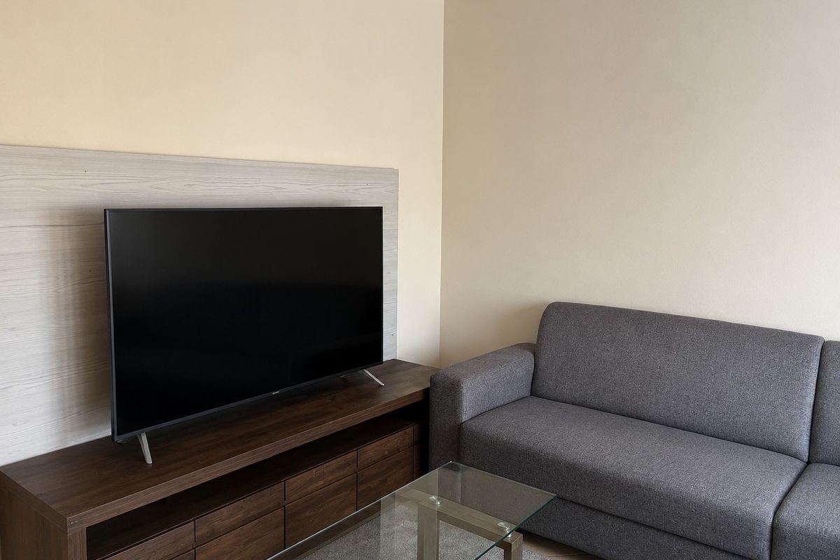 A living room area featuring neutral wall tones and decorative ceiling cornicing, providing a clean and functional space.