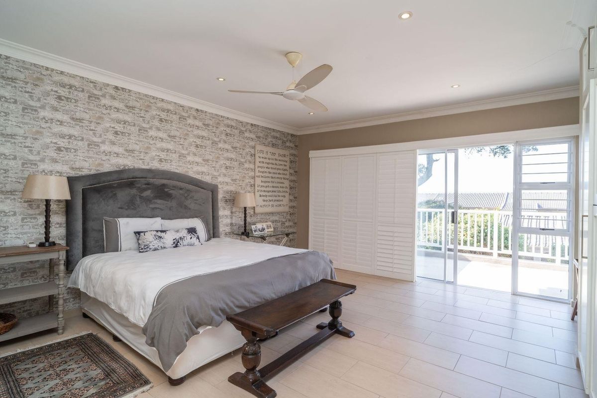 Spacious bedroom featuring a faux brick accent wall, tiled flooring, built-in cupboards, and sliding glass doors providing access to an outdoor balcony.