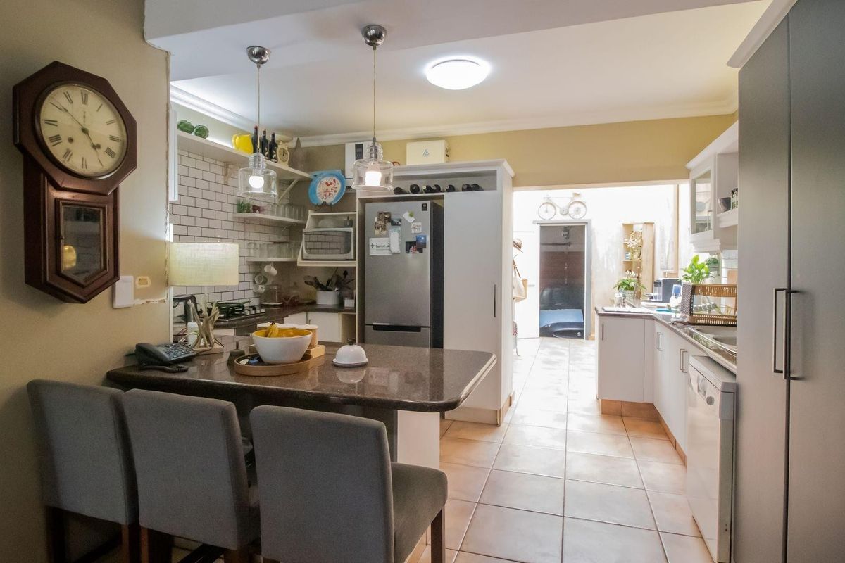 A functional kitchen featuring stone countertops, subway tile backsplash, and ample built-in cabinetry, leading through to a rear utility area.