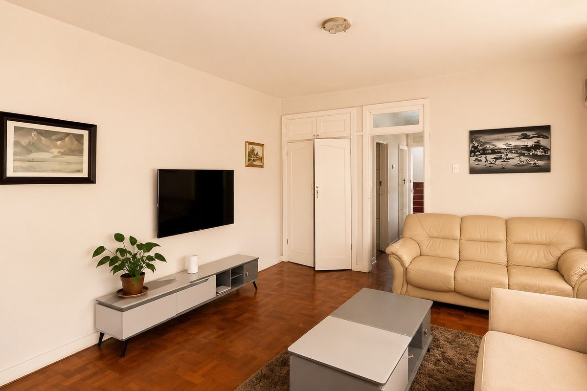 A well-maintained living room featuring classic parquet flooring, built-in storage cupboards, and an integrated air conditioning unit.