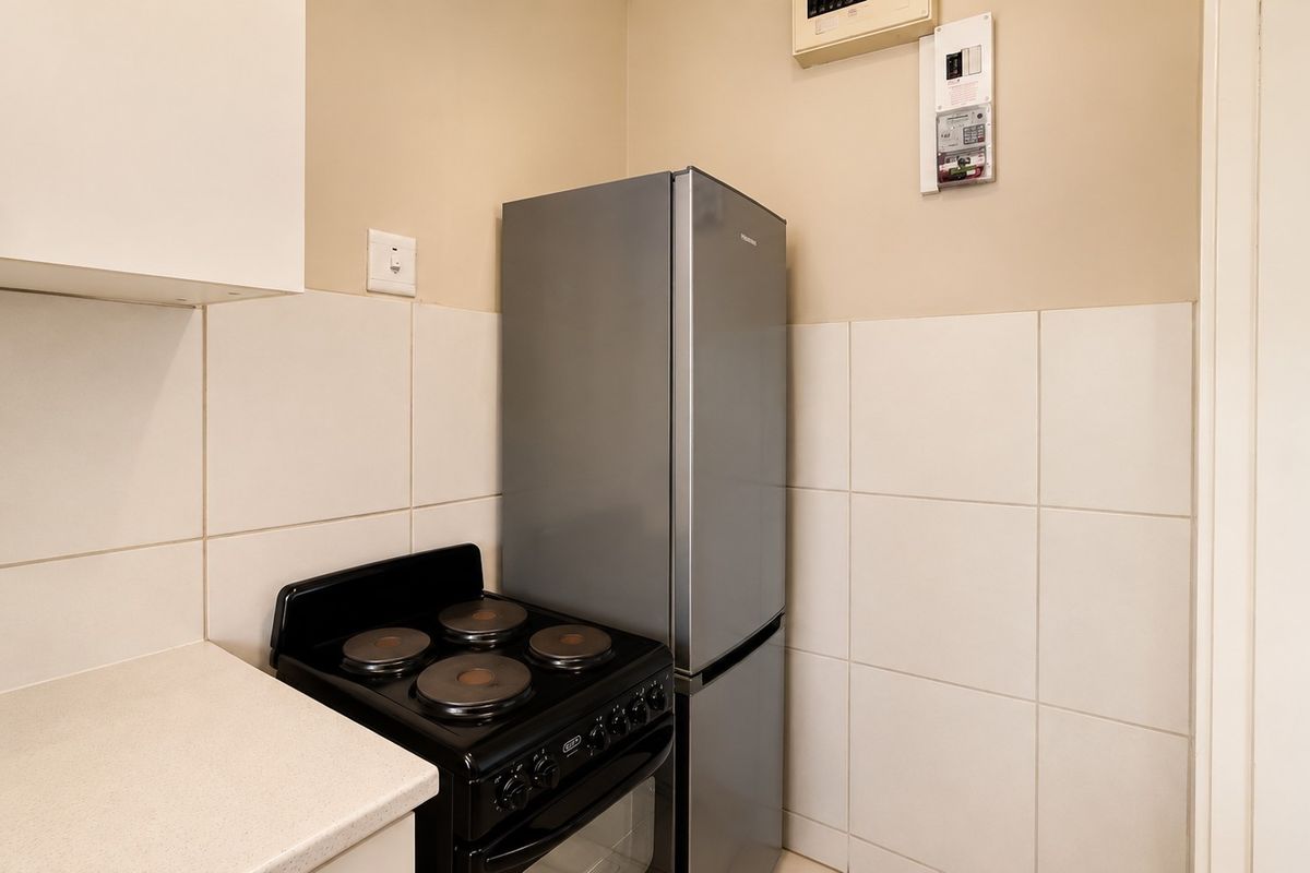 A compact kitchen area featuring tiled splashbacks, built-in cabinetry, and a functional countertop space.