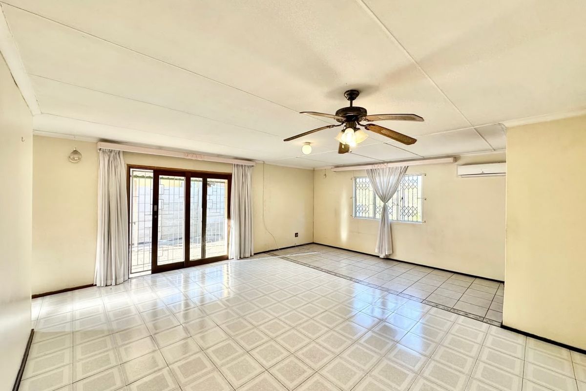 Spacious, empty living area featuring tiled flooring, a ceiling fan, split-system air conditioning, and sliding glass doors leading to the exterior.