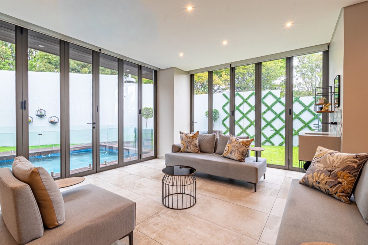 Modern living room featuring expansive bi-fold doors that open directly onto a private pool area and landscaped garden.