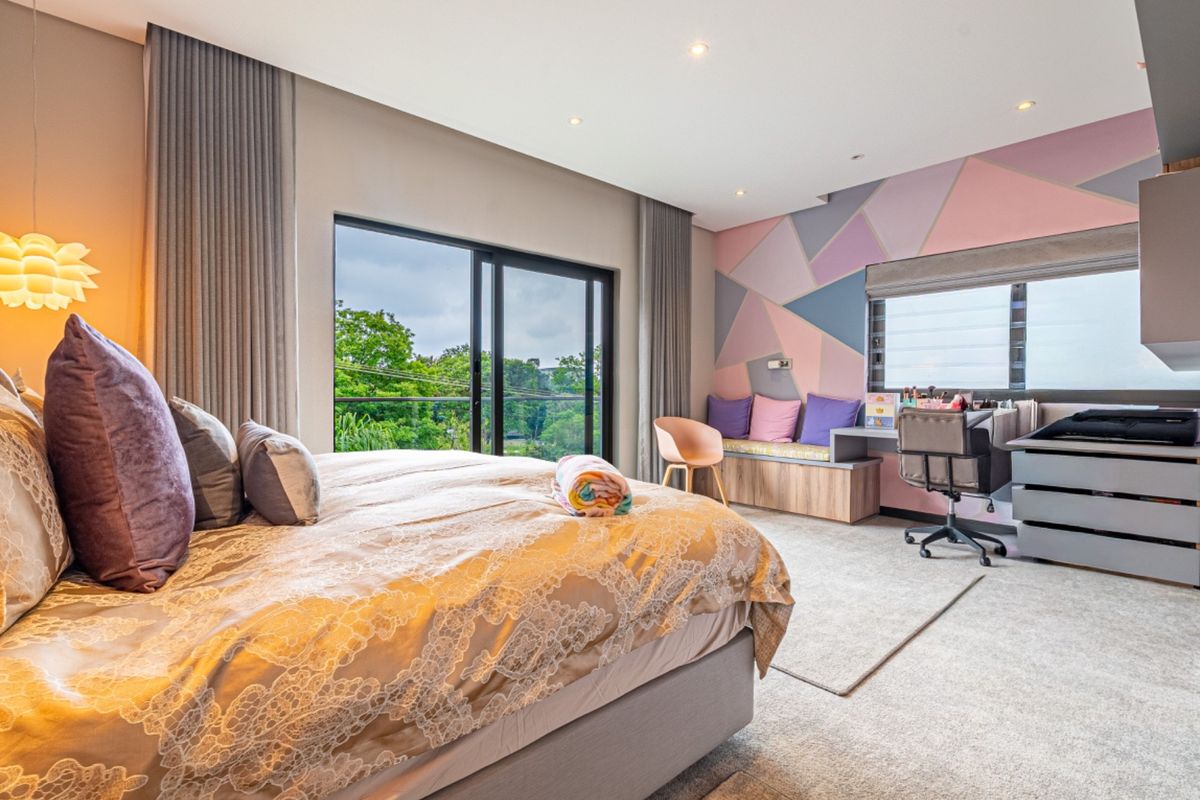 Spacious bedroom featuring a built-in desk, window seat, recessed lighting, and large sliding glass doors opening to an outdoor view.