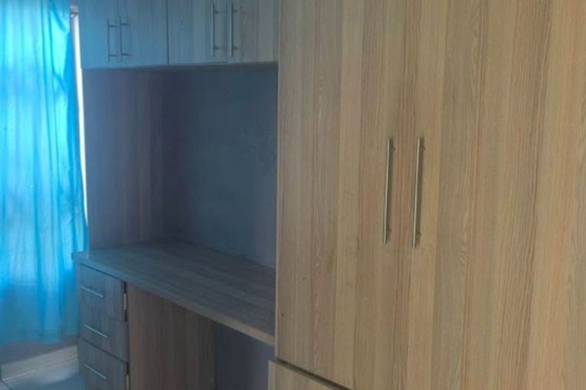 Bedroom featuring light wood-grain built-in cupboards and an integrated desk area with tiled flooring.