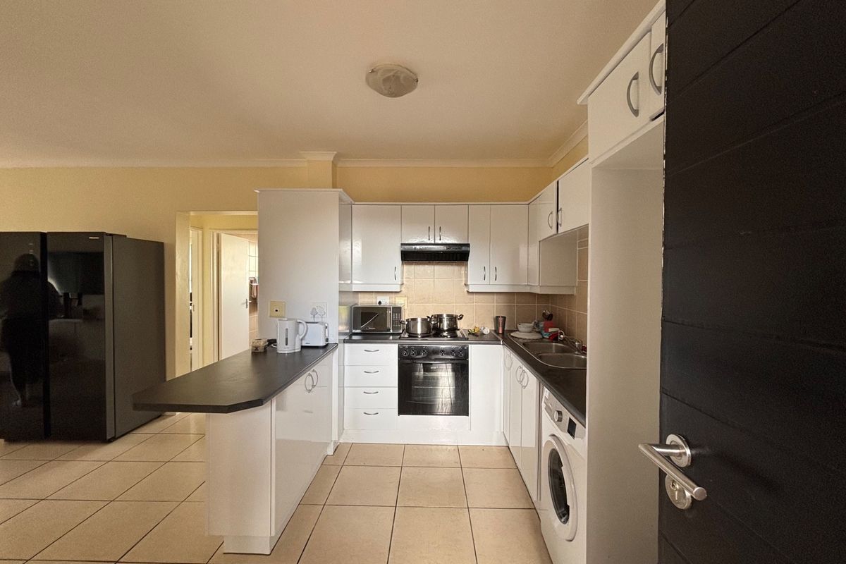 Functional kitchen featuring white cabinetry, built-in oven and hob, breakfast counter, and tiled flooring, providing a practical workspace for daily cooking.