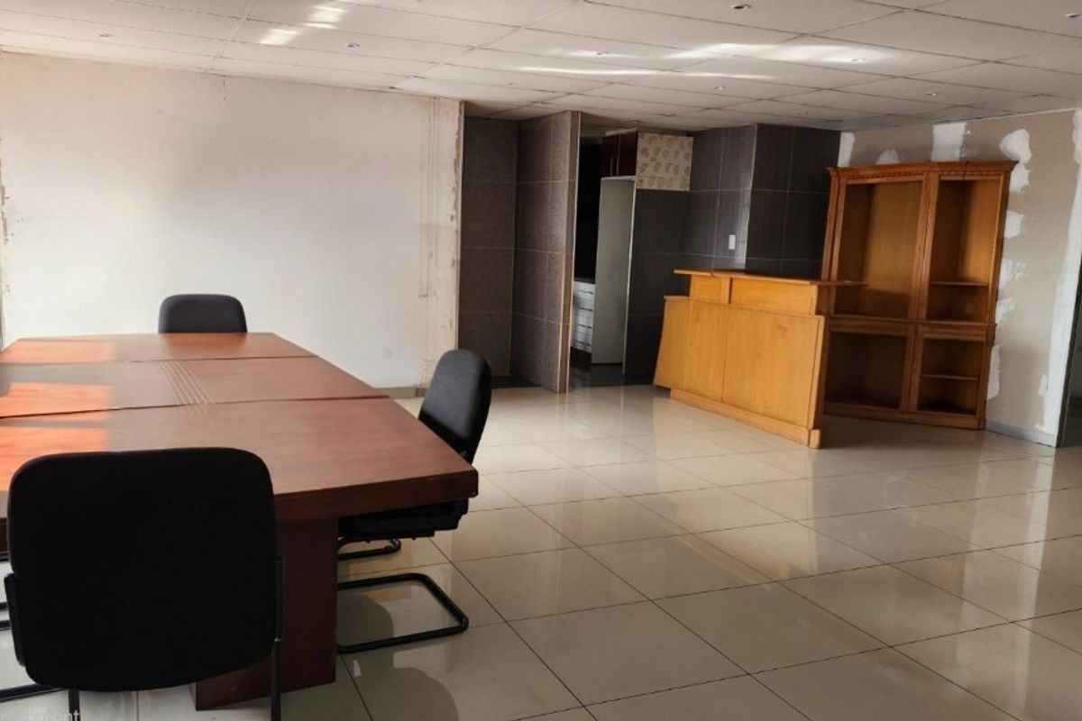 Spacious office area featuring tiled flooring and a suspended ceiling, currently requiring cosmetic wall repairs and finishing to reach its full potential.