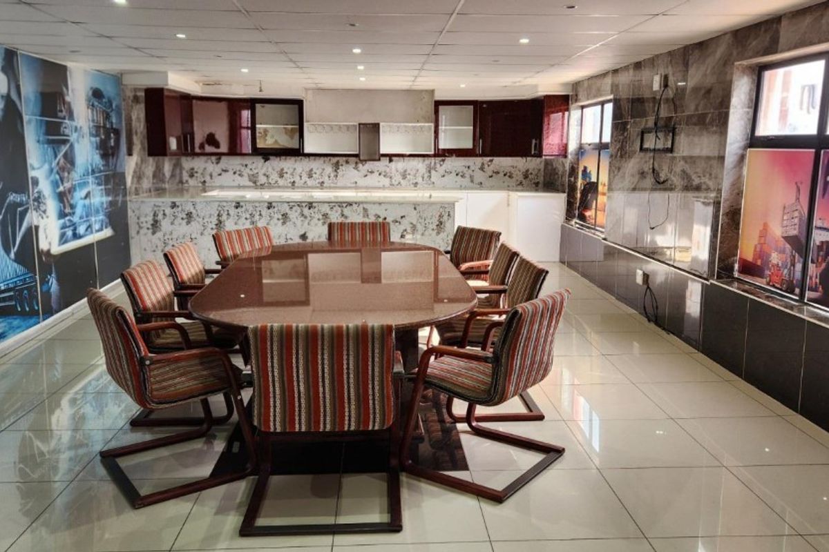 Spacious open-plan industrial office area featuring tiled flooring, suspended ceiling with recessed lighting, and integrated kitchen cabinetry with marble-effect wall finishes.