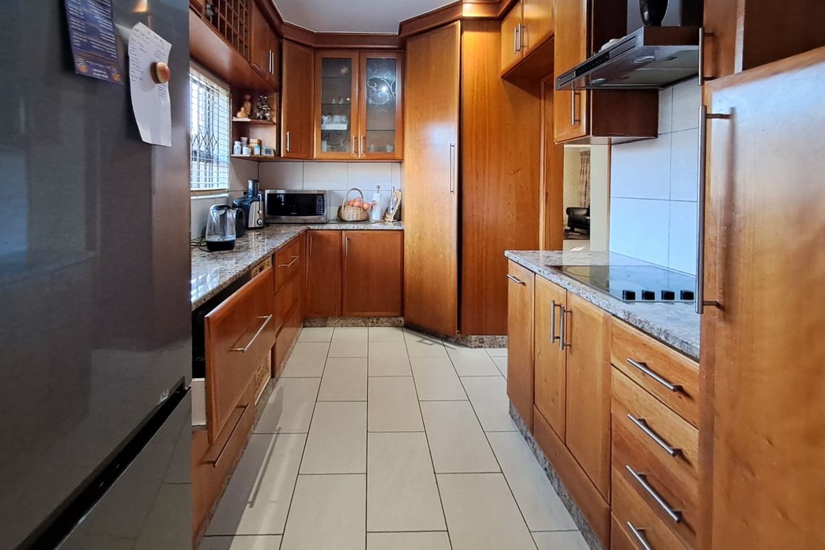 A functional kitchen featuring extensive wooden cabinetry, granite countertops, and tiled flooring, offering ample storage and workspace for meal preparation.